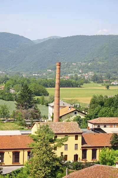 Large brick smokestack of a furnace and the hills — Stock Photo, Image