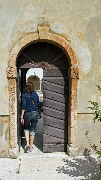 Frau, die in eine Tür eines alten Klosters tritt — Stockfoto