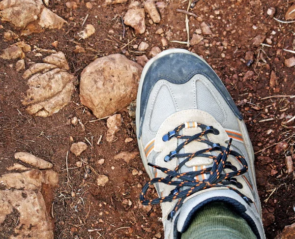 Shoe hiking along a trail of red earth and stones — Stock Photo, Image