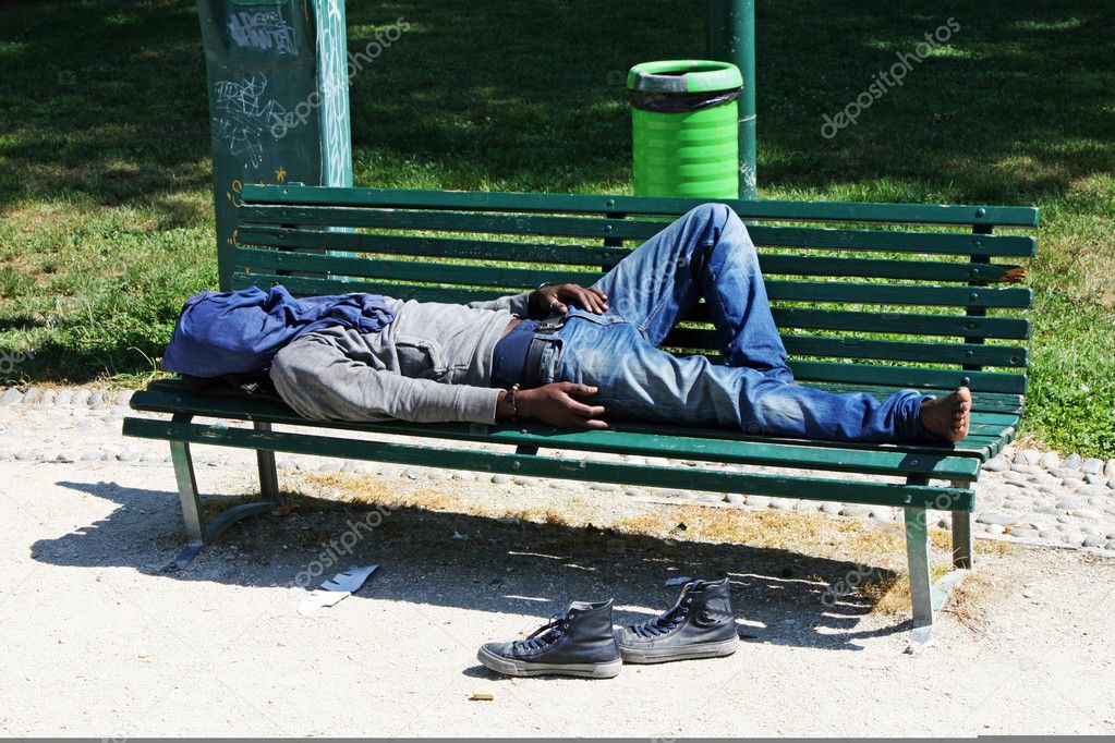 Poor marginalized homeless sleeping in a outdoor bench