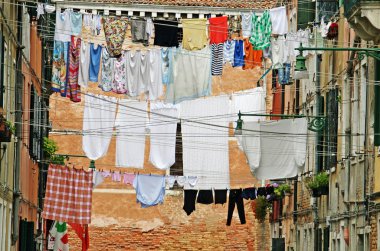 Street in venice with washing hung out to dry in the sun over the water cha clipart