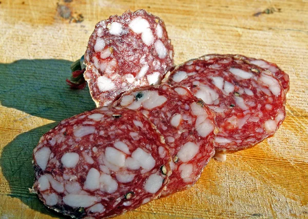 Sliced Tuscan salami on chopping freshly cut meat — Stock Photo, Image