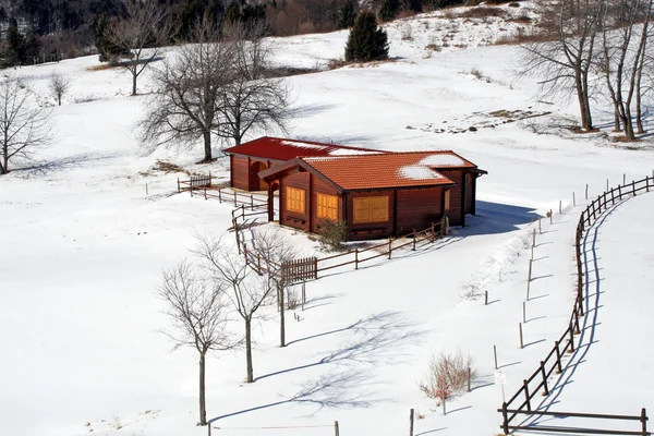 Cabaña de montaña aislada en medio de la pradera cubierta de nieve — Foto de Stock