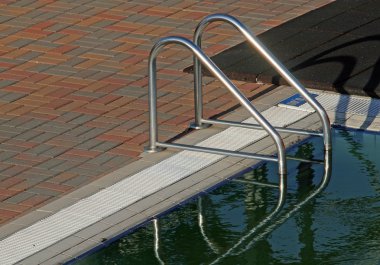 Ladder on the edge of a swimming pool clipart