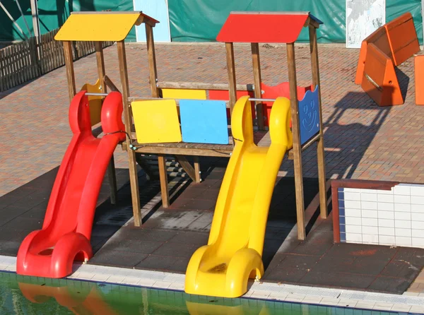 Red and yellow slides into a pool for the amusement of children — Stock Photo, Image