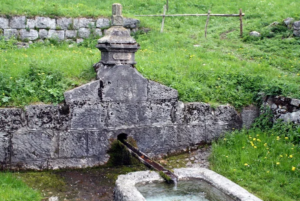 Oude stenen fontein met drenken en tanks — Stockfoto