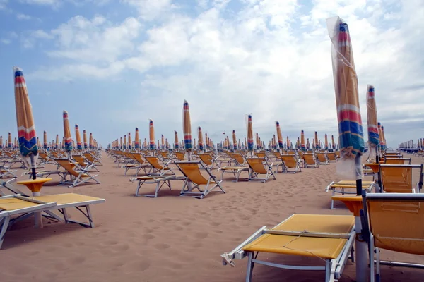 Set chiuso di sedie e ombrelloni in linea lungo la sabbia — Foto Stock