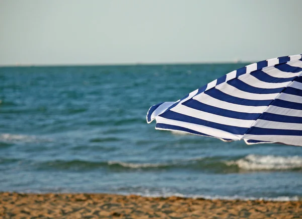 Ριγέ ομπρέλα στην παραλία και θάλασσα — Φωτογραφία Αρχείου