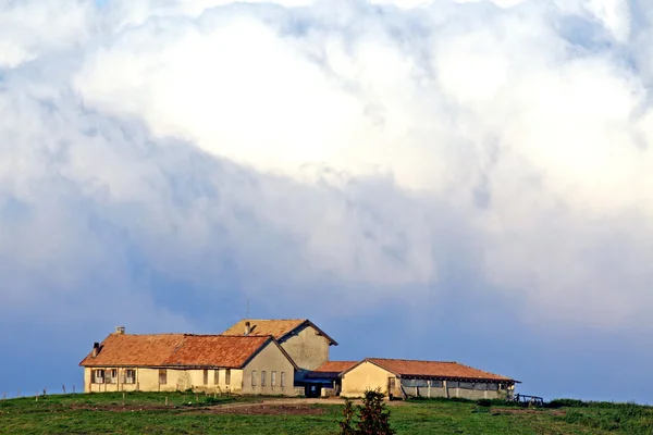 Estable sobre la colina con enormes nubes blancas — Foto de Stock