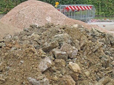 Piles of land and stones mined by excavation in site clipart