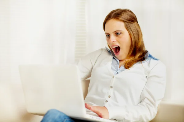 Mujer joven emocionada usando un ordenador portátil —  Fotos de Stock