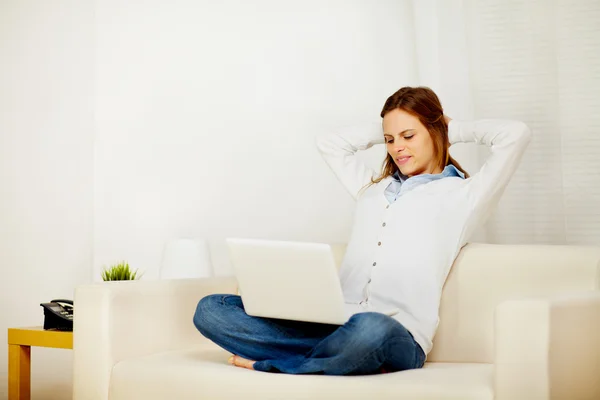 Прекрасна жінка відпочиває на дивані з ноутбуком — стокове фото