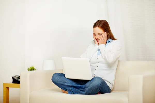 Mujer joven que trabaja en el sofá con un ordenador portátil —  Fotos de Stock