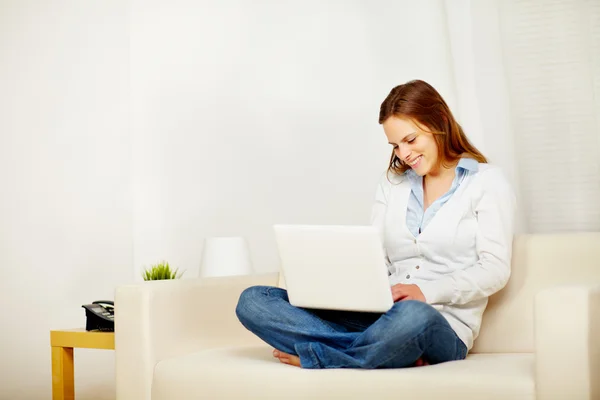 Mujer encantadora en el sofá con un ordenador portátil —  Fotos de Stock