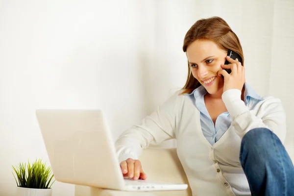 Mujer trabajando en el portátil y en el teléfono —  Fotos de Stock