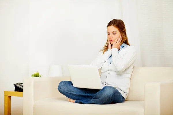 Casual girl working on sofa with a laptop — Stock Photo, Image