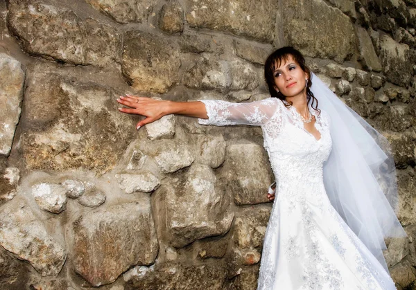 Sposa in piedi al muro di pietra — Foto Stock