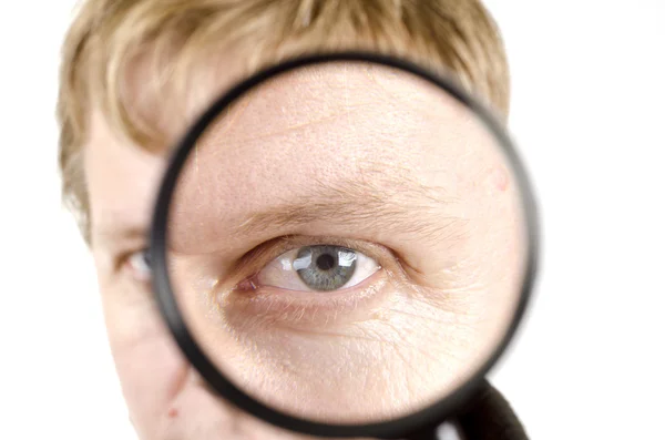 Portrait of young man looking through a magnifying glass — Stock Photo, Image