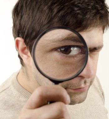 Young man looking throught magnifying glass clipart