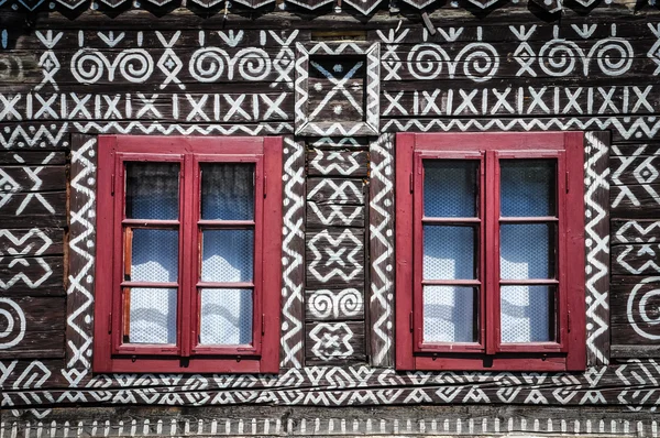 Finestre rosse su parete di legno di cottage tradizionale — Foto Stock