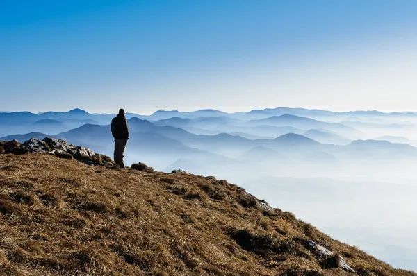 Colline di montagna nebbiose e silhouette di un uomo — Foto Stock