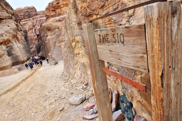 The Siq sign and entrance, the narrow slot-canyon, the entrance passage to — Stock Photo, Image
