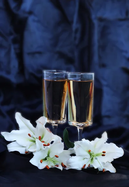 Glasses with wine and lily flower on black silk — Stock Photo, Image