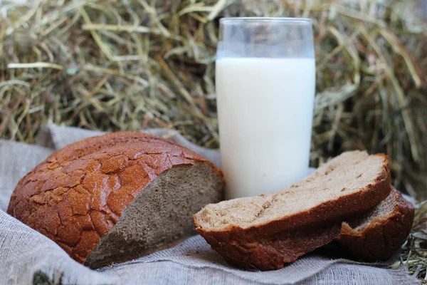 Pane e latte a fette marroni sul fieno — Foto Stock