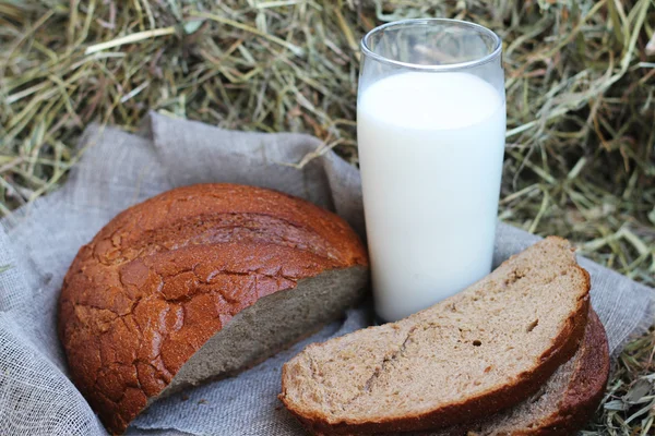 Бурый нарезанный хлеб и молоко на сене — стоковое фото