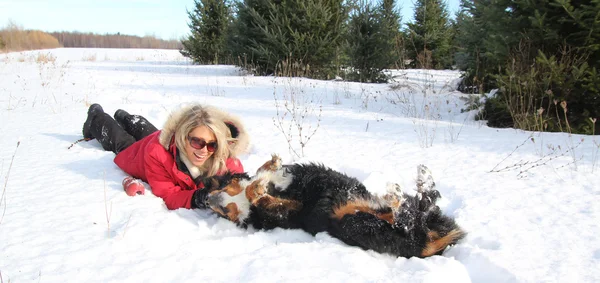 Mujer acariciando a su perro en la nieve — Foto de Stock