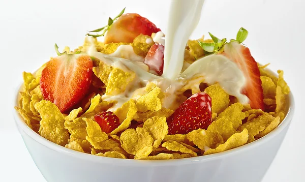 Milch in eine rote Cornflakes-Schüssel mit Erdbeeren auf weißem Hintergrund gießen — Stockfoto
