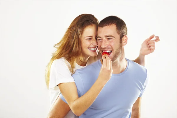 Happy young couple eating strawberries together — Stock Photo, Image