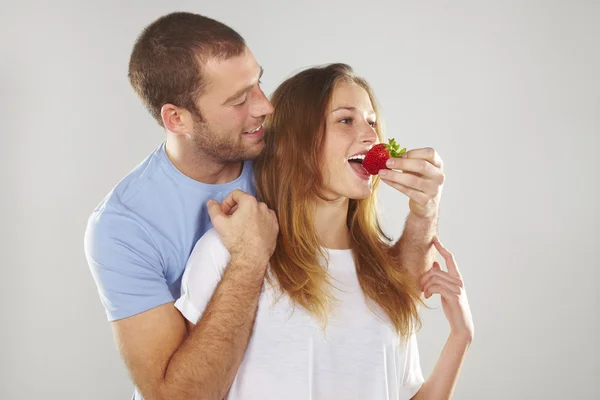 Happy young couple eating strawberries together — Stock Photo, Image