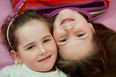 Smiling sisters lying in bed clipart