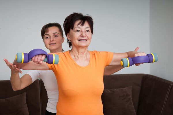 Mature woman exercising with trainer