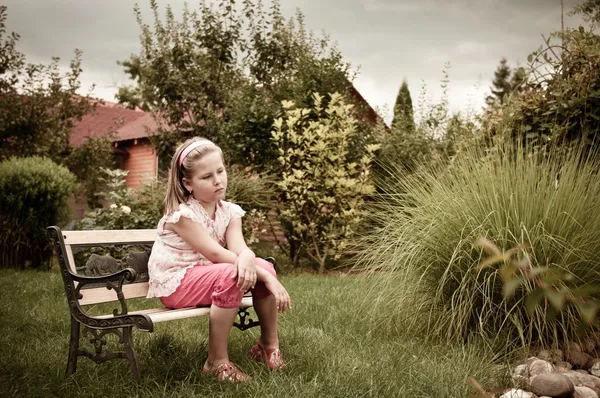 Dívka sedící na lavičce na dvorku — Stock fotografie