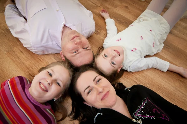 Ouders met twee kinderen, liggend op de vloer — Stockfoto