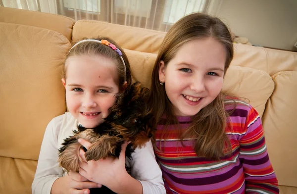 Sisters sitting on sofa with their dog — Stock Photo, Image