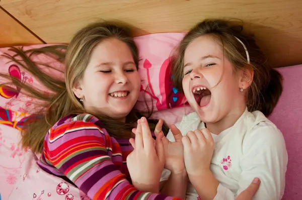 Sestry se smíchem, ležící v posteli — Stock fotografie