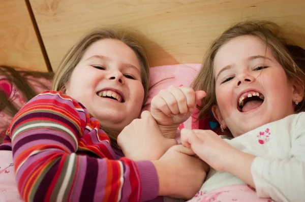 Schwestern lachen im Bett liegend — Stockfoto