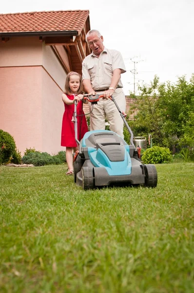 Senior man with lawn mower and child — Stockfoto