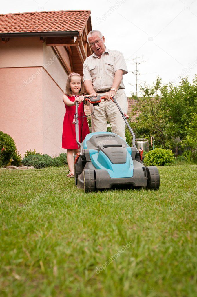 Senior man with lawn mower and child