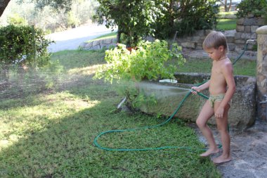 Boy playing with a garden hose clipart