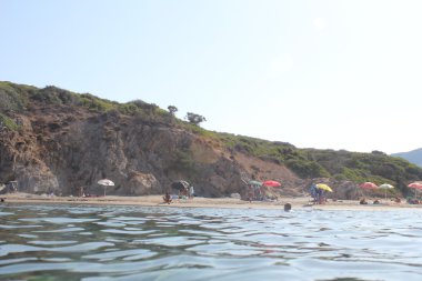 Sardinya kıyılarında, deniz, kum ve taşları mavi gökyüzü ile