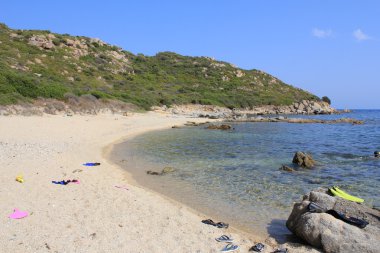 Sardinya kıyılarında, deniz, kum ve taşları mavi gökyüzü ile