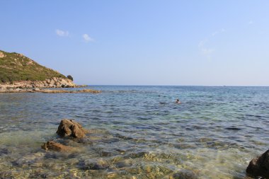 Sardinya kıyılarında, deniz, kum ve taşları mavi gökyüzü ile