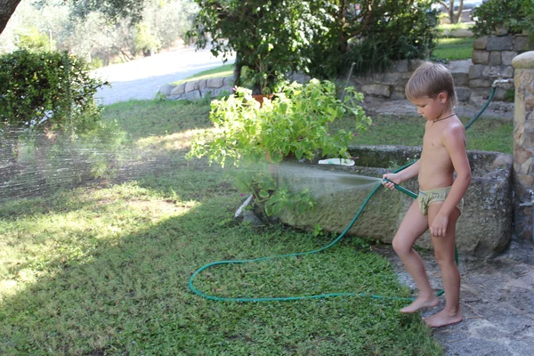 Menino brincando com uma mangueira de jardim — Fotografia de Stock