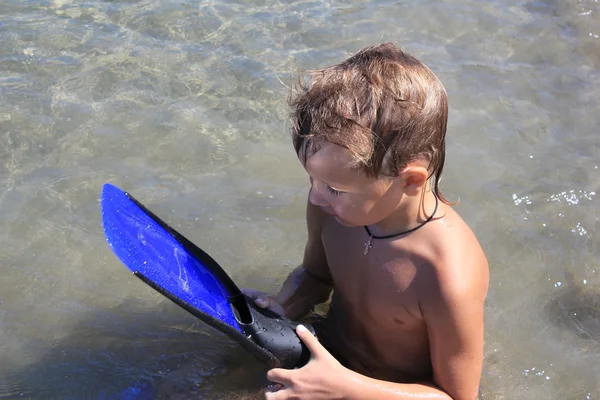 Chlapec sedí u vody na tropické pláži — Stock fotografie