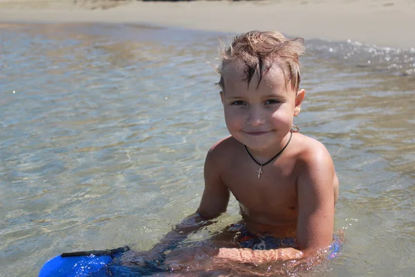Αγόρι κάθεται κοντά στο νερό σε τροπική παραλία — Φωτογραφία Αρχείου