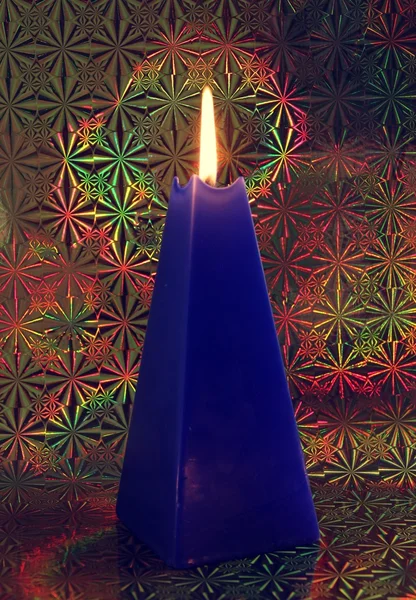 Палаюча блакитна свічка на декоративному глянсовому фоні — стокове фото
